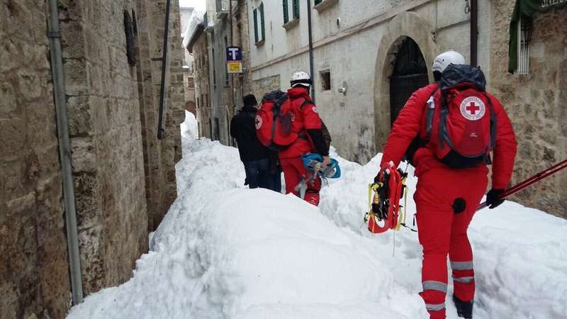 Un volontario di Croce Rossa avanza nella neve munito di racchette per raggiungere le persone rimaste isolate