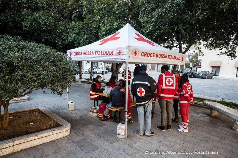 Volontari e operatori di Croce Rossa parlano con un ragazzo migrante a Trapani