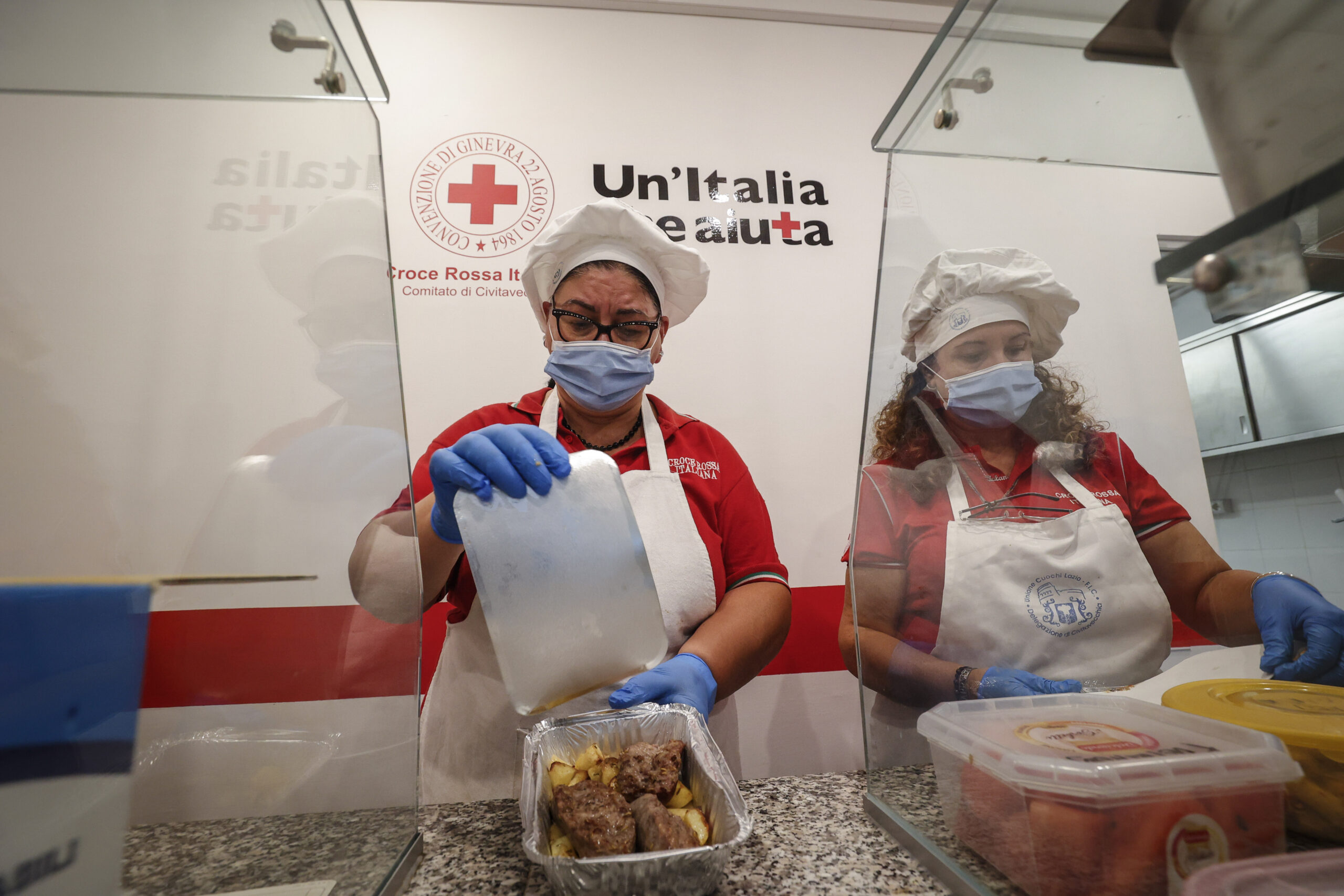 Members of the Italian Red Cross prepare hot meals to be distributed to the people in need and the homeless in Civitavecchia