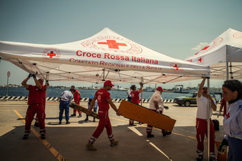 volontari croce rossa allestiscono stand accolgienza 