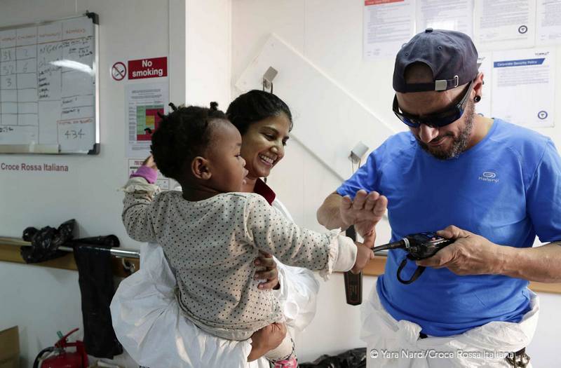 Un medico visita un bambino piccolo, la mamma sorride. Foto: Yara Nardi - Croce Rossa