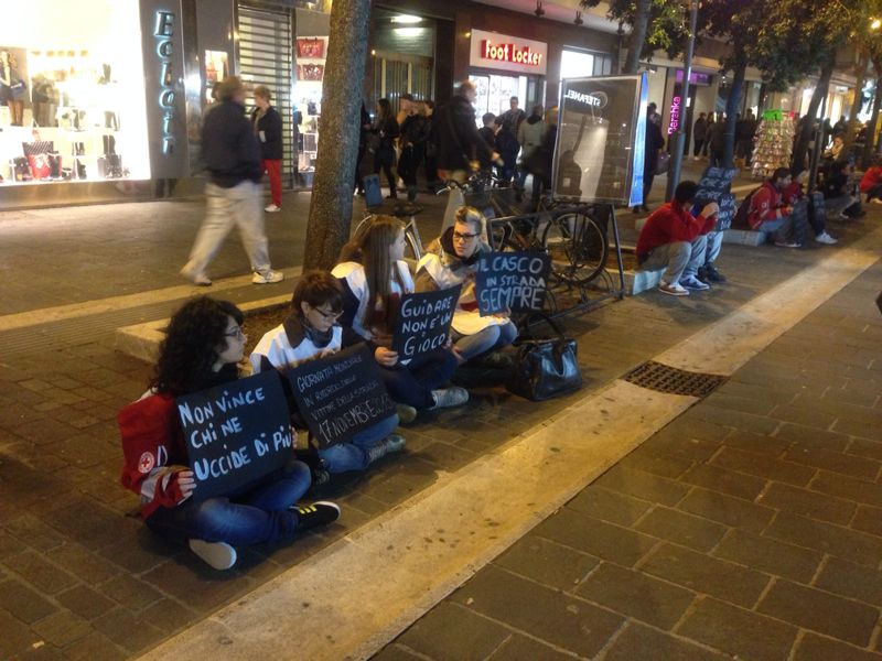 Volontari seduti a terra con cartelli