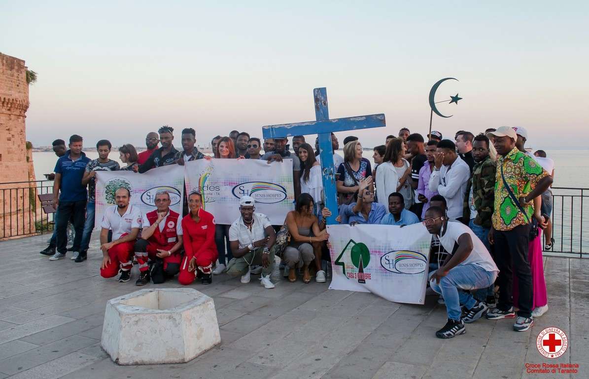 Volontari e operatori della Croce Rossa di Taranto insieme a ragazzi e ragazze di diverse origini si preparano per la fiaccolata