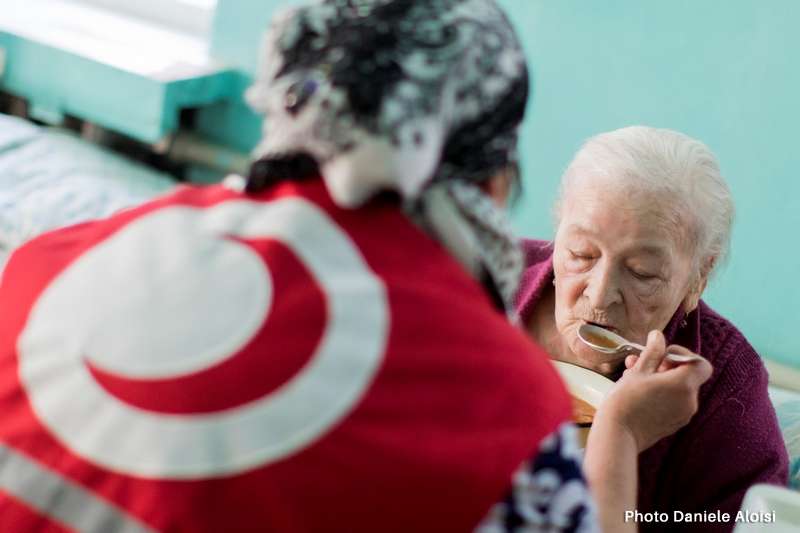 Kirghizistan: una volontaria della Mezzaluna Rossa aiuta una persona anziana a mangiare.  Foto: Daniele Aloisi