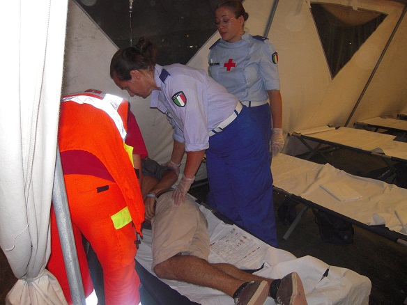 Un medico e due infermiere volontarie assisteono un paziente nella tenda