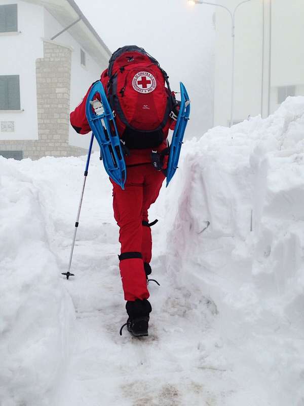 Un volontario di Croce Rossa avanza nella neve munito di racchette per raggiungere le persone rimaste isolate