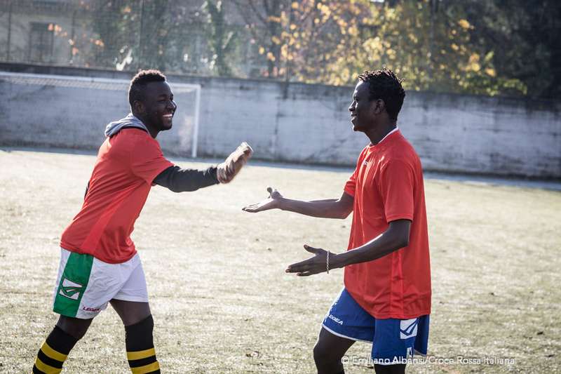 Due giocatori si scambiano il cinque durante gli allenamenti della  squadra di calcio dilettantistica del centro accoglienza migranti gestito dalla Croce Rossa a Bresso