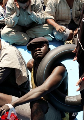 Emergenza umanitaria: un giovane migrante attende ancora stretto ad una camera d'aria gonfiata, un salvagente di fortuna