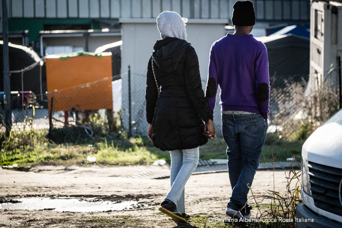 Un ragazzo e una ragazza si tengono per mano nel centro di accoglienza migranti di Croce Rossa a Settimo Torinese