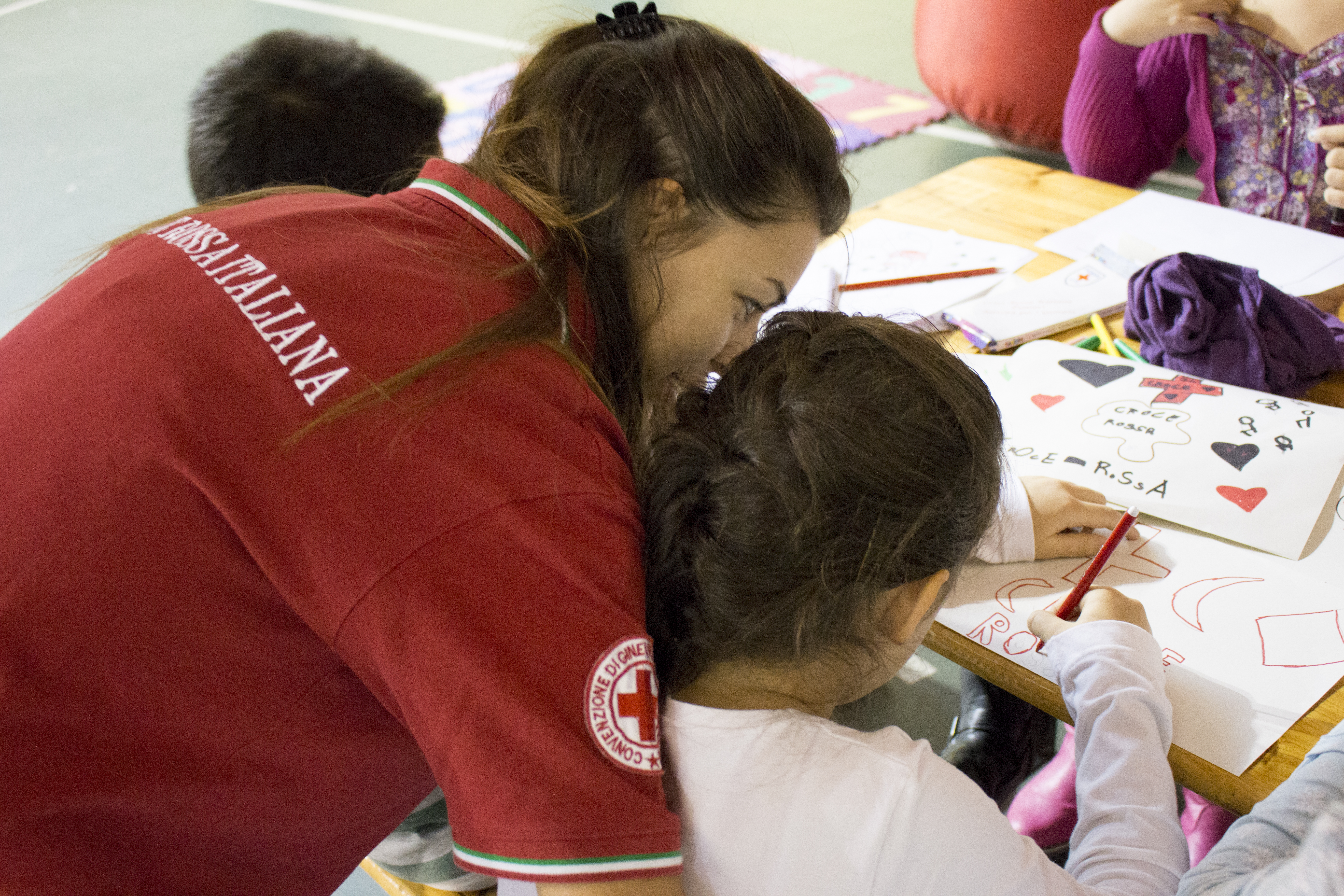 Una volontaria insegna disegnando le attività di Croce Rossa ai più piccoli.
