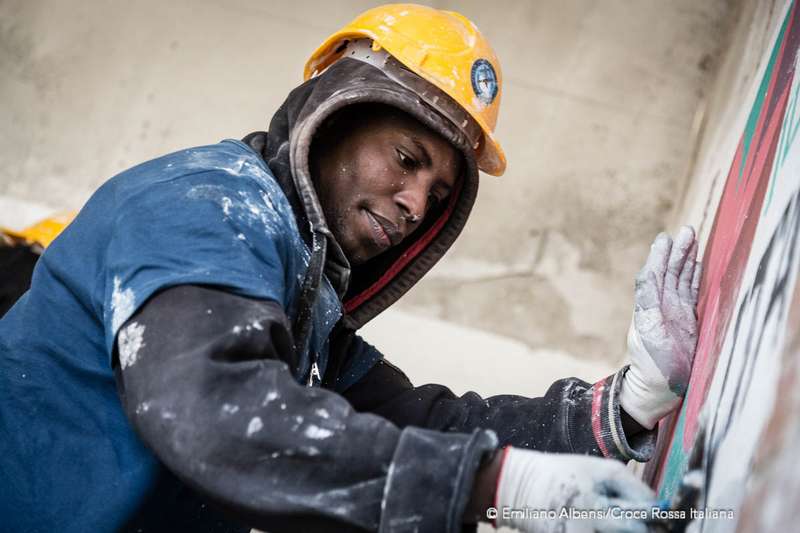 Un ragazzo migranti impara a fare il muratore attraverso un programma di formazione avviato da Croce Rossa