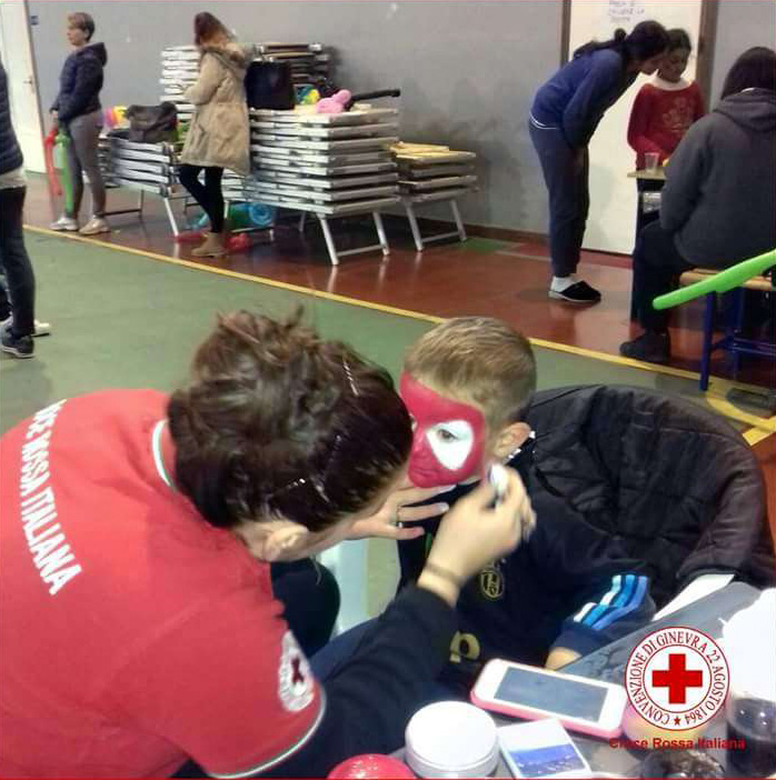 Una volontaria della Croce Rossa trucca un bambino in uno dei centri di accoglienza allestiti dopo il terremoto nel Centro Italia