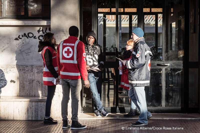 Volontari e operatori di Croce Rossa parlano con un ragazzo migrante a Trapani