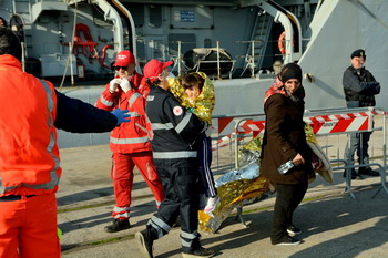 Volontari croce rossa aiutano migranti sbarcati a Taranto 